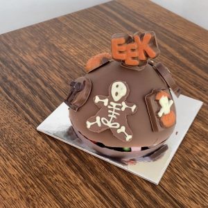 Photograph of a chocolate Halloween Smash cake with lollies inside and chocolate skeletons decorating the exterior